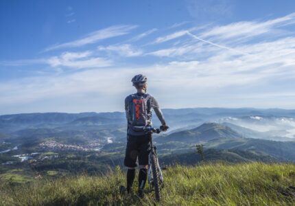 biker-holding-mountain-bike-on-top-of-mountain-with-green-161172
